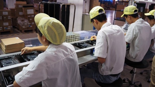 직원들이 메인보드 기판에 트랜지스터, 각종 부품들을 장착하고 있다